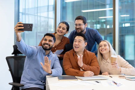 A diverse group of colleagues taking a selfie together in a modern office setting, showcasing...