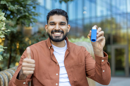 A cheerful man with an inhaler shows a thumbs-up outside. He appears to be happy and healthy,...