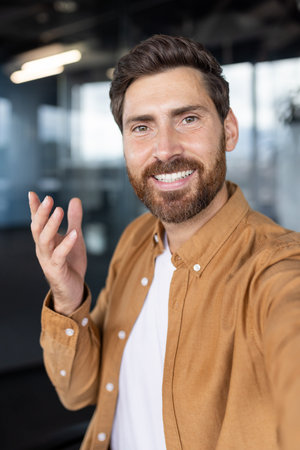A man smiles during a video call, wearing a casual shirt and expressing himself with gesturesの写真素材