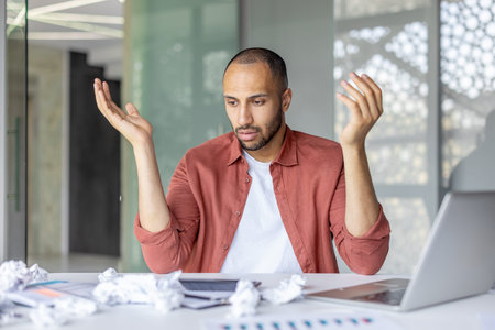 Sad frustrated financier accountant at workplace inside office. Man sitting at desk with laptop,...