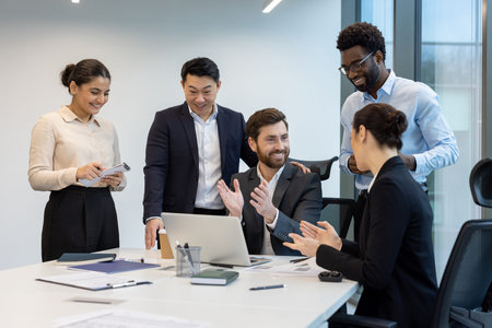 Diverse business team celebrates a success in a modern office setting. Colleagues are gathered...