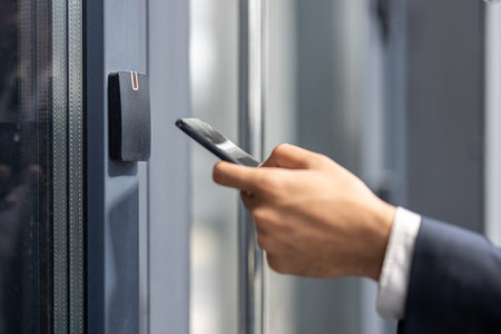 A person in a suit uses a smartphone near a door access system, possibly for security or entry.