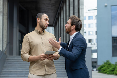 Two men engaged in a heated argument outdoors, possibly a work-related disputeの写真素材
