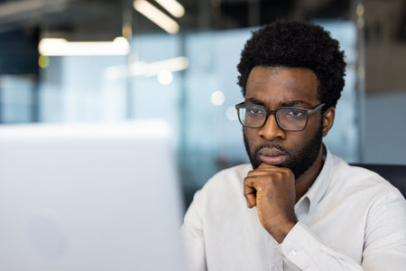A professional individual deeply concentrating while working on a computer in a contemporary office...