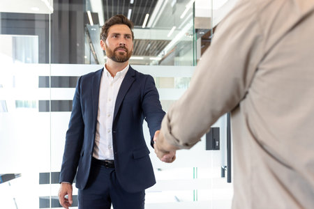 Professional welcome gesture between two individuals in a contemporary office environment,...