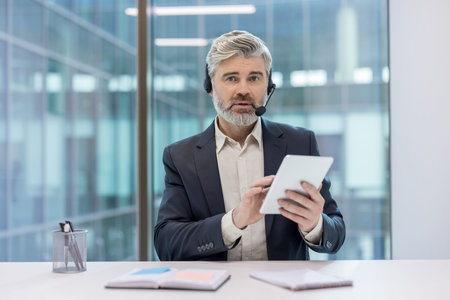 Business professional wearing a headset interacting with a tablet in a contemporary office setting.