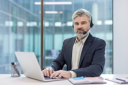 Business professional providing service while working remotely using a laptop and headset. Office...