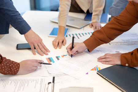 Business team analyzing financial data and signing documents during a productive meeting,...