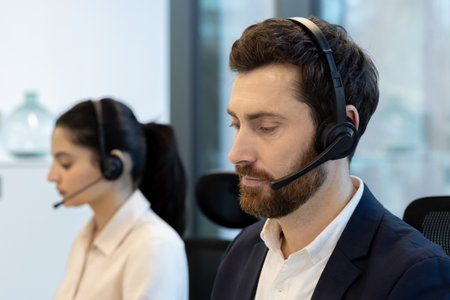 Call center agent with headset working at desk, focused on providing client assistance and technical support while communicating with customers in a modern office environmentの写真素材