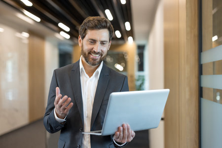 Happy businessman smiling and gesturing during a virtual meeting, discussing business online while...