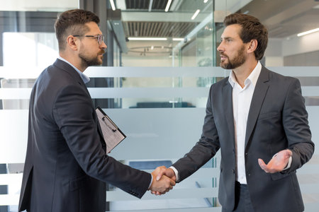 Businessmen making a professional handshake in an office setting, representing successful negotiation, partnership, and agreement between two male colleagues closing a business dealの写真素材