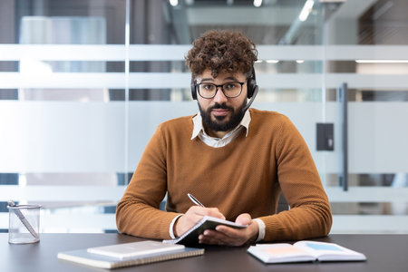 Young man wearing headset and glasses, working as a customer support consultant or attending a...