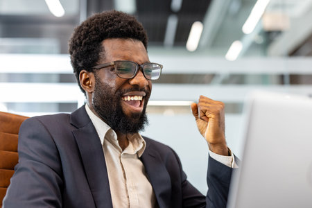 Adult businessman showing excitement and joy, clenching his fist in a gesture of triumph while...