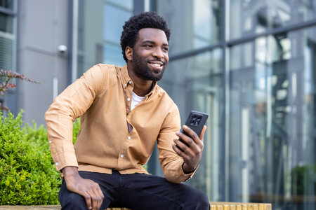 Smiling man finding joy and connection while using a mobile phone, embracing technology for...