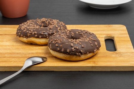 Chocolate donuts on the cutting board with cup and plateの写真素材