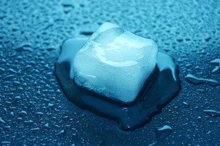 colored ice cube melted in water on reflection の写真素材