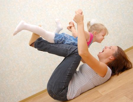 Mother and her little daughter on wooden  floorの写真素材