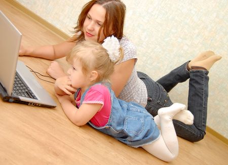 Mother and daughter with laptop on wooden  floorの写真素材