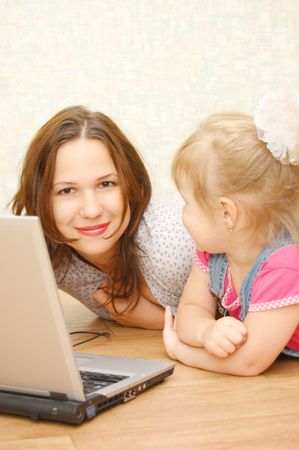 Mother and daughter with laptop on wooden  floorの写真素材