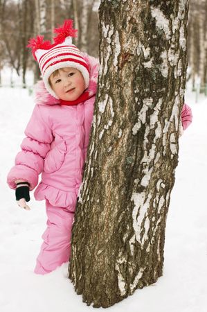 little girl has hidden behind a treeの写真素材