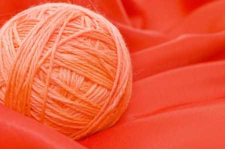 Ball of threads on a red fabricの写真素材
