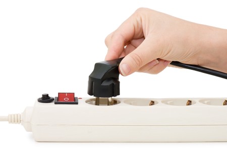 hand with an electric plug and socket is isolated over whiteの写真素材