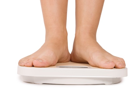 Female feet on scales isolated on whiteの写真素材