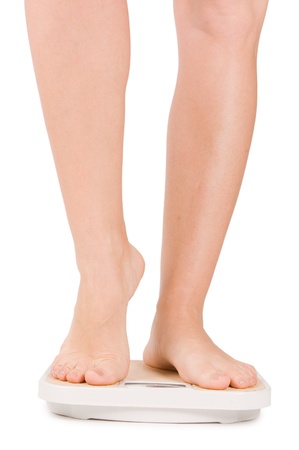 Female feet on scales isolated on whiteの写真素材