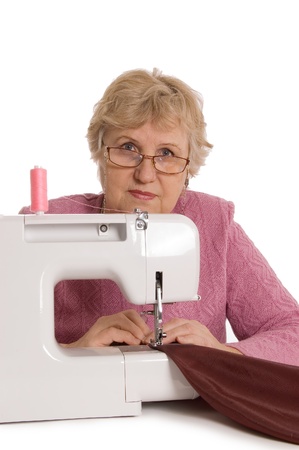 The elderly woman sews on the sewing machineの写真素材