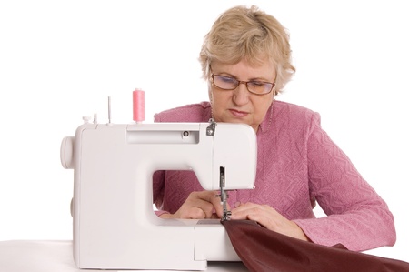 The elderly woman sews on the sewing machineの写真素材