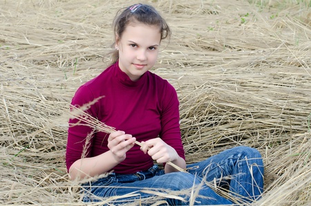 The girl Sits on a dry grassの写真素材