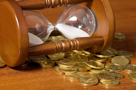 Hourglasses and coin On a wooden table
