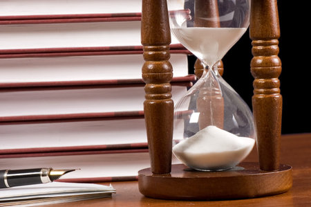 Hourglasses and book on a wooden table