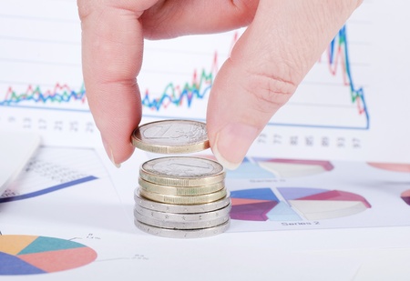 Coins in hand against business of diagrammesの写真素材