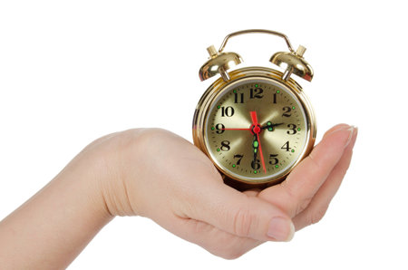 The alarm clock in female hands isolated