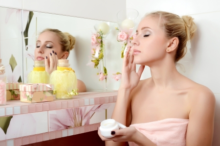 Woman blonde puts on face a creamの写真素材