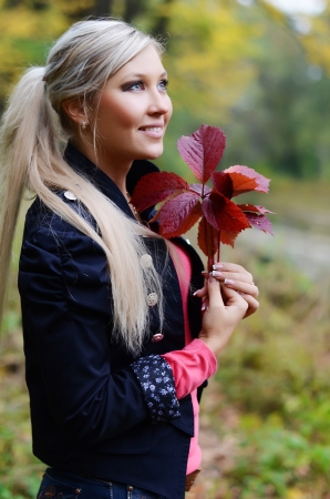 The beautiful young woman with autumn leavesの写真素材