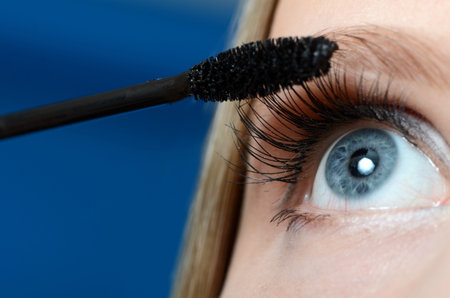 Woman applying mascara on her eyelashes  macro