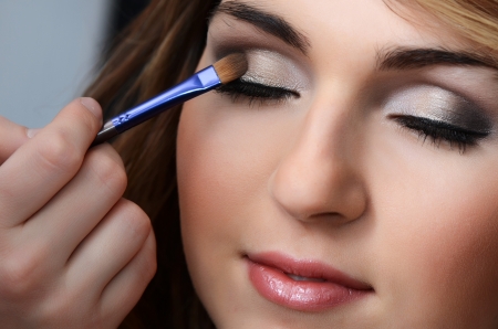Beautiful girl put the makeup on the faceの写真素材