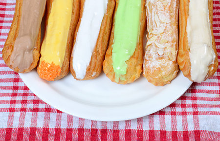 Eclair with a cream on a plate close up