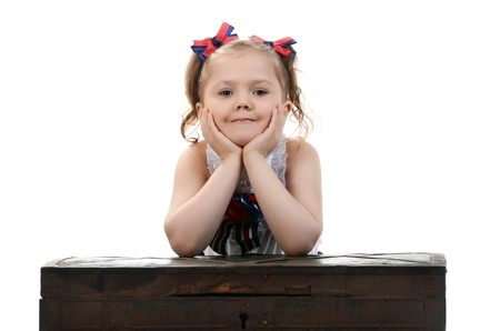 beautiful young female child model sitting on a chest on white backgroundの写真素材