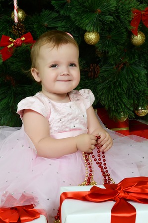 The little girl at a Christmas fur-tree with giftsの写真素材