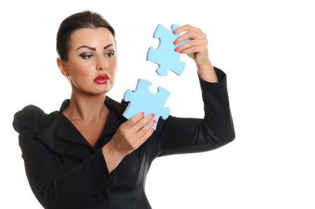 Young  confident business woman joining two jigsaw puzzle pieces on white backgroundの写真素材