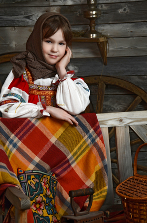 Beautiful girl in russian costume sitting in a traditional interiorの写真素材