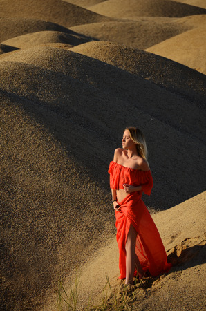 The beautiful girl in a red dress in sandの写真素材