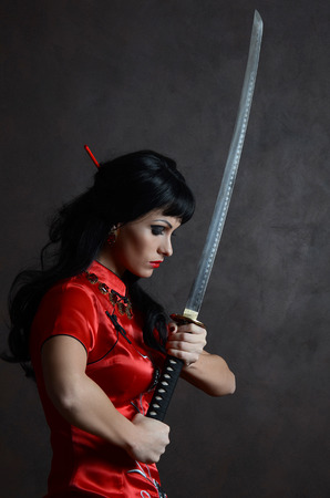 Beautiful geisha in kimono with samurai swordの写真素材