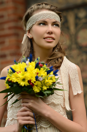 Beautiful natural young blonde smiling woman on field keep in hand yellow flowersの写真素材