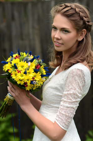 Beautiful natural young blonde smiling woman on field keep in hand yellow flowersの写真素材