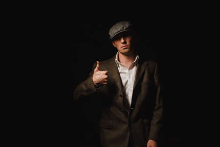 A man in a classic jacket and cap. A man in the dark.の写真素材