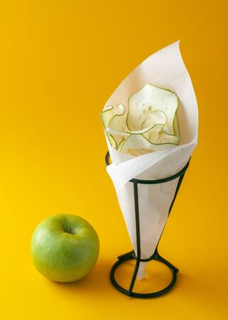 Healthy eating concept. Green apple and apple chips on a yellow backgroundの写真素材
